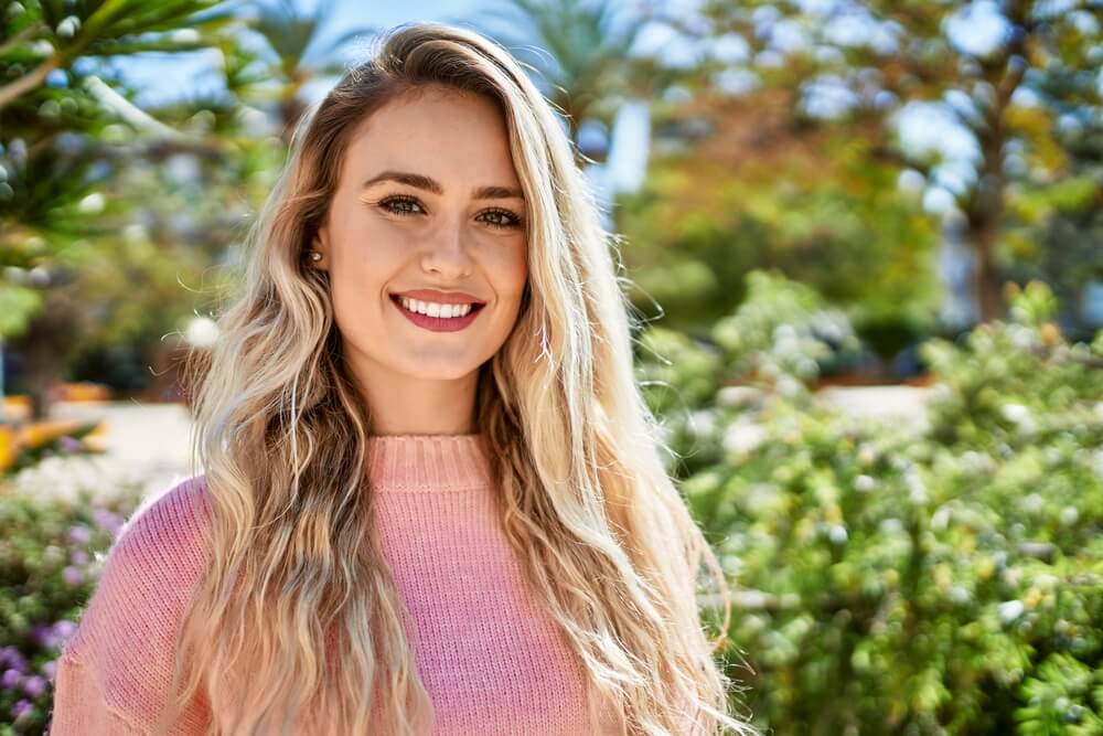 Young blonde woman smiling at the park